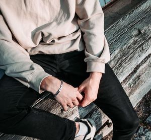 Midsection of man sitting on wood