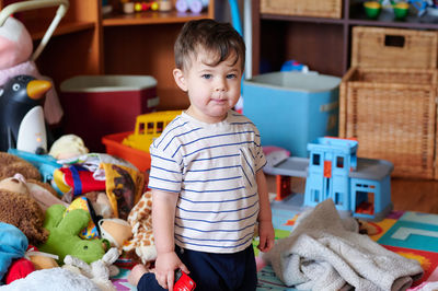 Cute little boy surrounded by toys