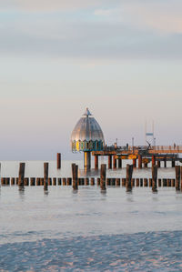 View of wooden posts in sea against sky