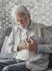 Portrait of senior man sitting on sofa at home