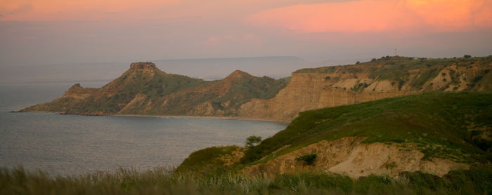 Scenic view of sea and mountains against sky during sunset