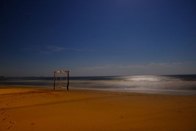 Lifeguard hut on beach against blue sky