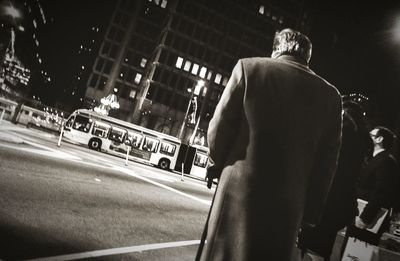 Rear view of man standing on road in city