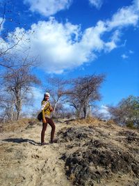 Woman standing by tree against sky