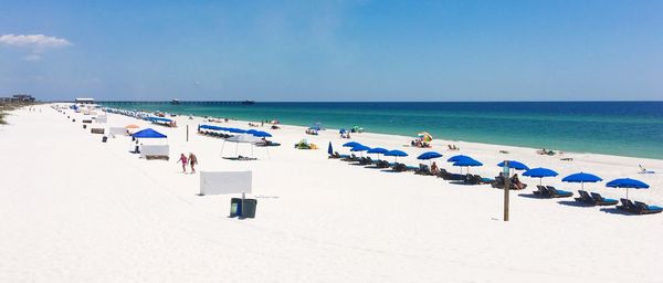 Panoramic view of people at beach against blue sky during summer