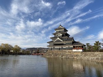 Traditional building by lake against sky