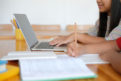 Midsection of woman using mobile phone while sitting on table