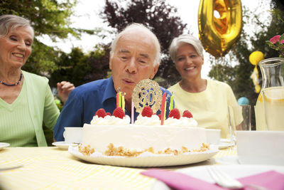 Senior man blowing candle on 80th birthday cake