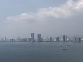 Sea by buildings against sky in city