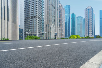 City street by modern buildings against sky