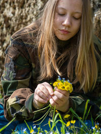 Teenager caucasian girl picking up flowers in springtime in a garden outdoors a sunny day