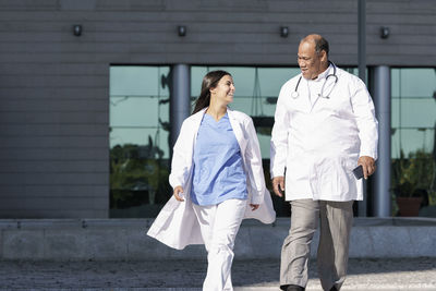 Doctors wearing lab coat walking against hospital