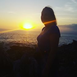 Woman standing at beach during sunset