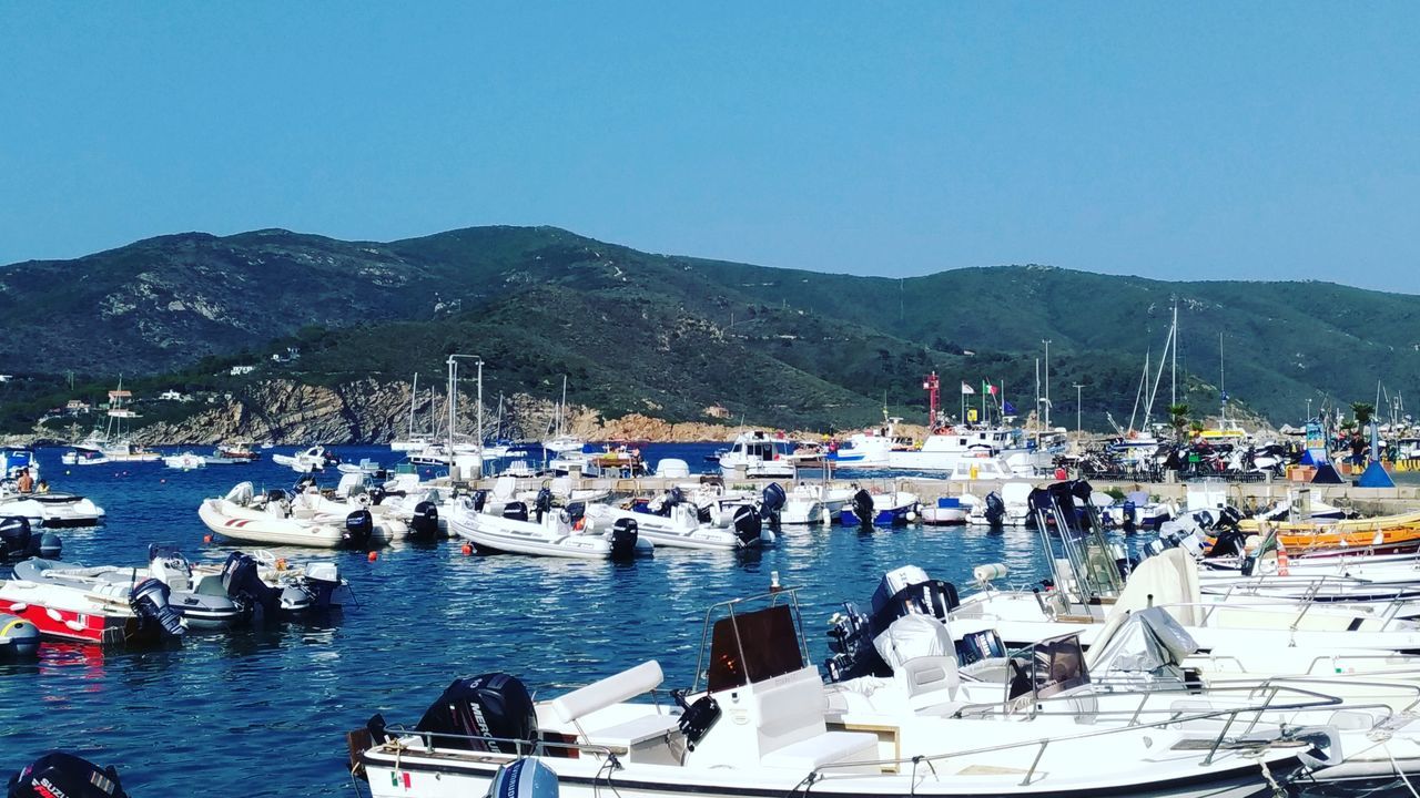 BOATS MOORED IN SEA AGAINST BLUE SKY