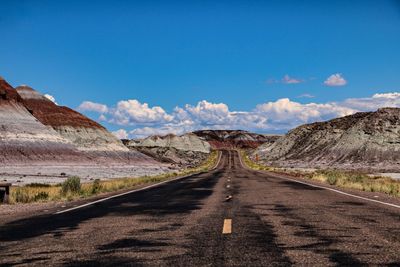 Empty road along landscape and mountains against sky