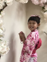 Portrait of cute girl standing against wall