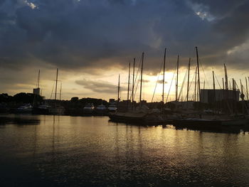 Sailboats moored at harbor against sky during sunset