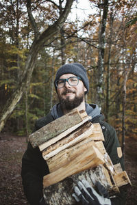 Portrait of man carrying firewood in forest