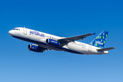 Low angle view of airplane flying against clear blue sky