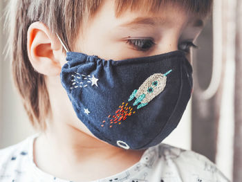 Boy with handmade protective mask on face. embroidered space theme. quarantine coronavirus covid19.
