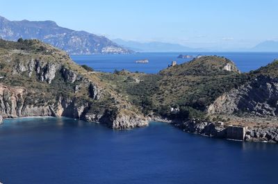 Scenic view of sea and mountains against blue sky