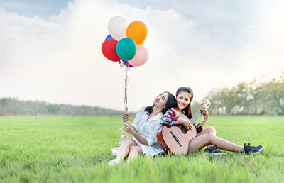 Rear view of women sitting on balloons at field