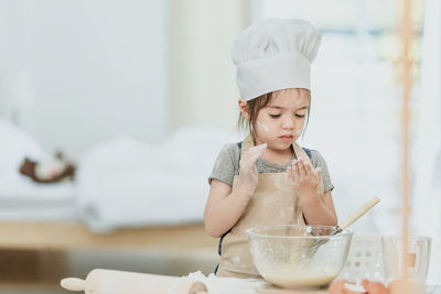 Girl looking away while sitting on table at home