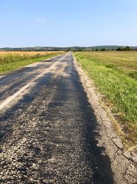 Country road amidst field against sky