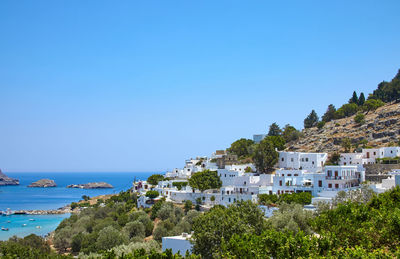 Scenic view of townscape by sea against clear blue sky