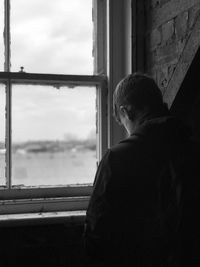 Rear view of boy looking through window