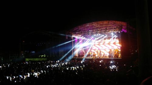 Crowd at music concert against sky at night