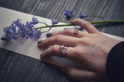 Midsection of woman holding purple flower on table