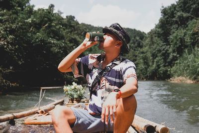 Rear view of boy sitting on boat against river