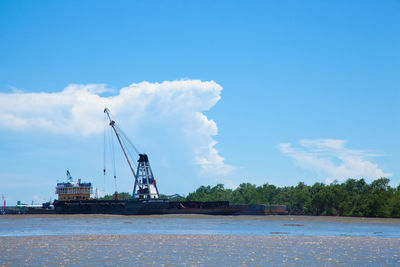 Cranes at commercial dock against blue sky