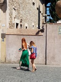 Rear view of women walking on street against buildings