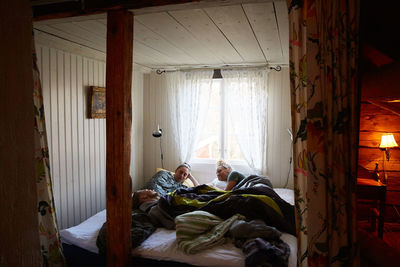 Male and female friends talking while relaxing on bed at home