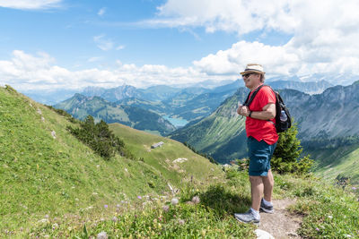 Rear view of woman standing on mountain against sky