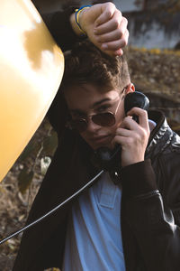 Portrait of teenage boy wearing sunglasses using telephone