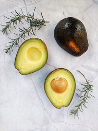 Fresh avocado with herbs and lemons lies on the table on white background. flat lay. top view.