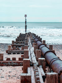 Scenic view of sea against sky with groyne and pipe