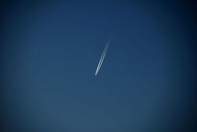 Low angle view of vapor trail against clear blue sky