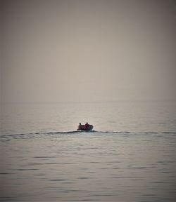 Boat sailing in sea against clear sky