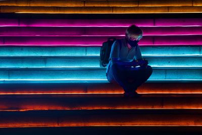 Full length of woman standing against illuminated wall