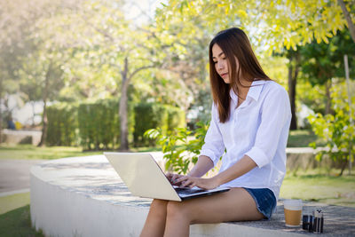 Young woman using mobile phone while sitting outdoors
