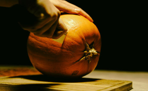 Cropped hand of person cutting pumpkin during halloween