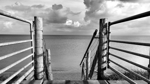 Pier on sea against cloudy sky