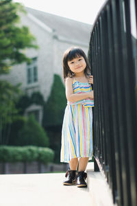 Full length portrait of girl standing by railings