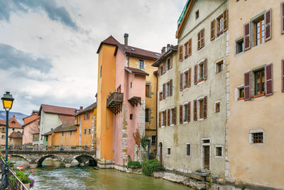 Buildings by canal against sky in city