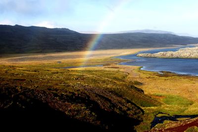 Scenic view of rainbow over mountain against sky