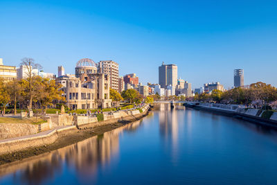 View of river and buildings against blue sky